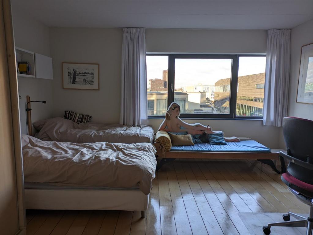 una mujer sentada en una cama en un dormitorio en Almere Centre half an hour train to Amsterdam en Almere