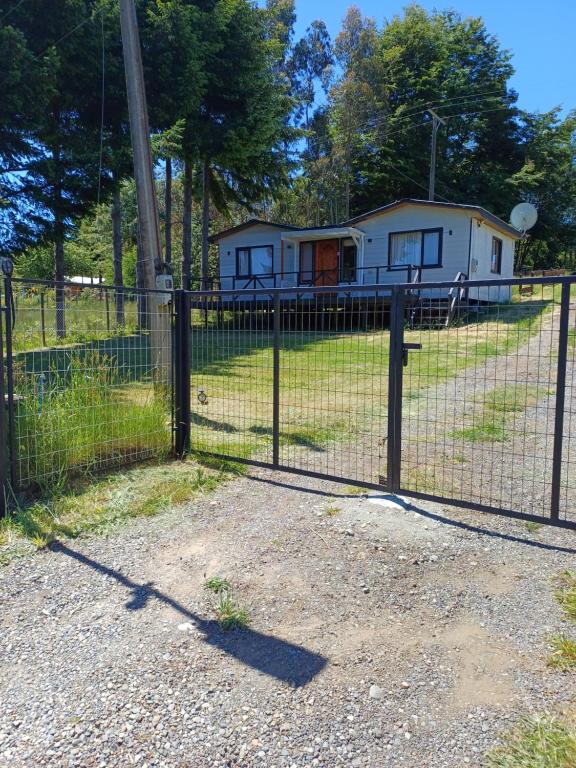 una recinzione con una casa sullo sfondo di CABAÑAS LOMAS DE YECO a Valdivia