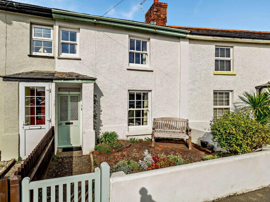 a white house with a bench in the front yard at 4 Bed in Bude CRESC in Bude