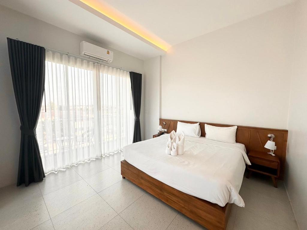 um quarto com uma cama com lençóis brancos e uma grande janela em Choe Hotel Banbueng em Ban Bung