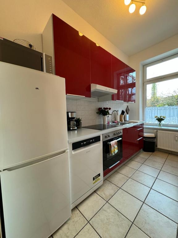 uma cozinha com um frigorífico branco e armários vermelhos em Attraktive Wohnung im grünen Hinterhof em Schwerin