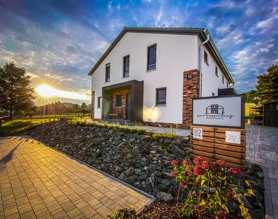 a white house with the sunset in the background at FeWo Zur Wasserburg in Oelsnitz/Vogtland