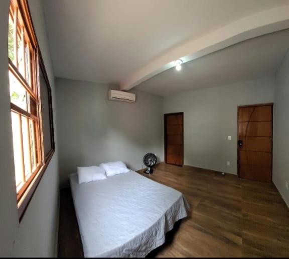 a bedroom with a white bed and a window at Chacara in Atibaia