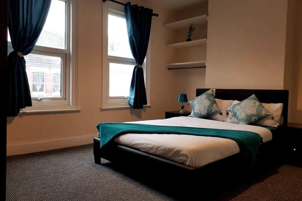 a bedroom with a bed and two windows at Central Reading 4 Bedrooms Free Parking in Reading