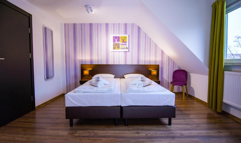 ein Schlafzimmer mit einem großen Bett mit weißer Bettwäsche in der Unterkunft Hirsch Hotel Hanau in Hanau am Main