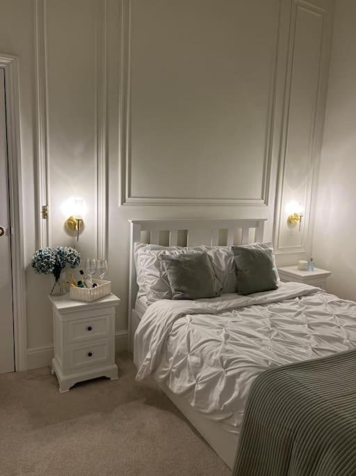 a white bedroom with a bed and a night stand at Victorian Stay in Ocean village in Southampton