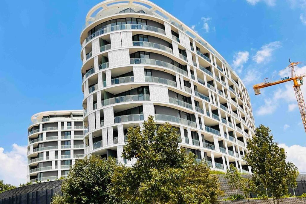 um edifício branco alto com um guindaste à frente. em Newton’s Place - Luxury styled 2 BD Apartment em Midrand