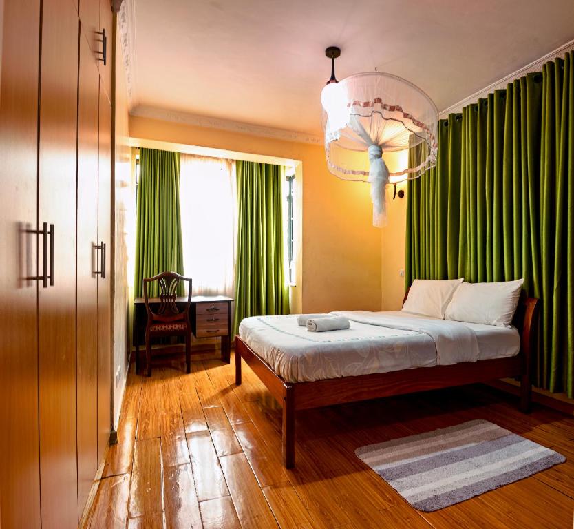 a bedroom with a bed with green curtains and a window at MANI HOMES in Nairobi