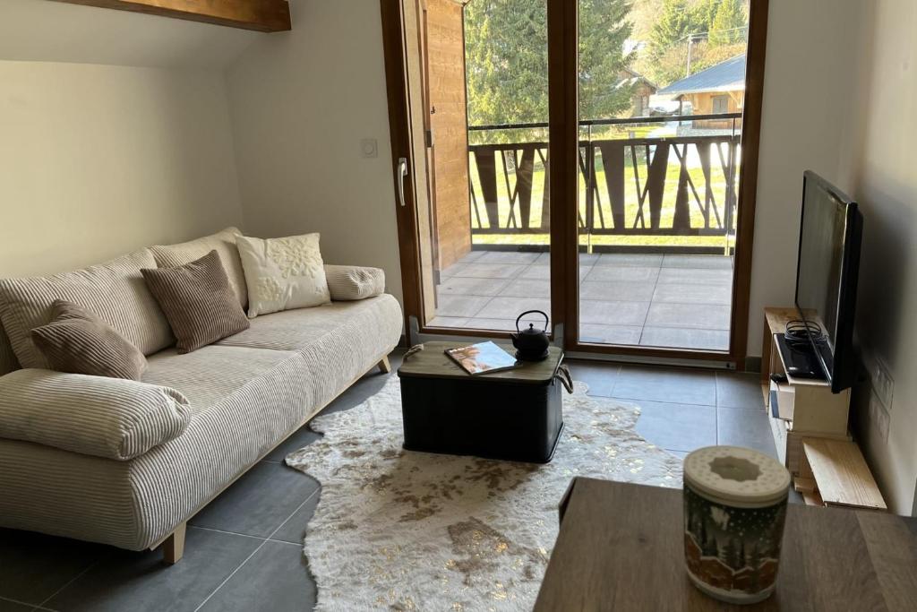 a living room with a couch and a tv at Superbe appartement 4 personnes au pied des pistes in La Féclaz