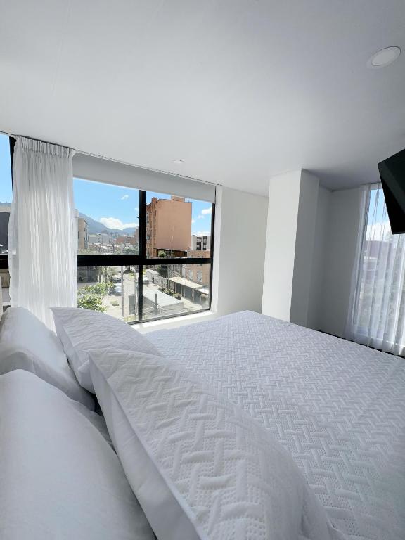 a bedroom with a white bed and a large window at Loft 60 Movistar arena 403 in Bogotá