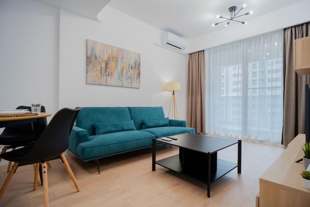ein Wohnzimmer mit einem blauen Sofa und einem Tisch in der Unterkunft Politehnica Park Residence: Modern Comfort in Bukarest
