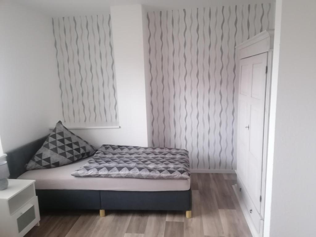 a small bedroom with a bed and a white wall at Ferienwohnung I Sarrebriese in Bottmersdorf