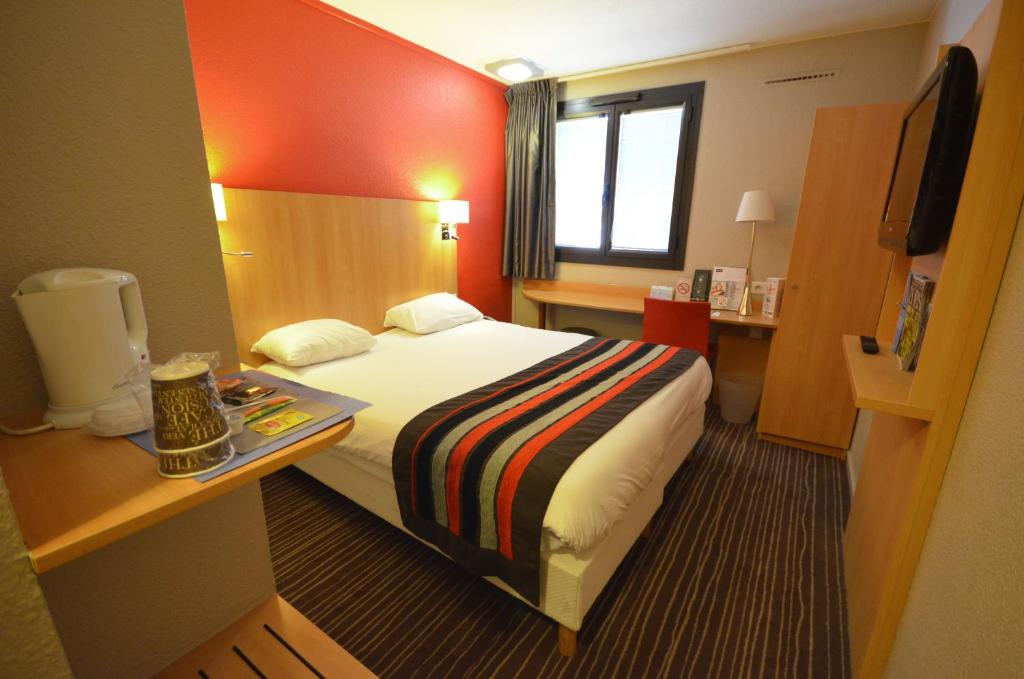 a hotel room with a bed and a desk at Kyriad Dijon Est Mirande in Dijon