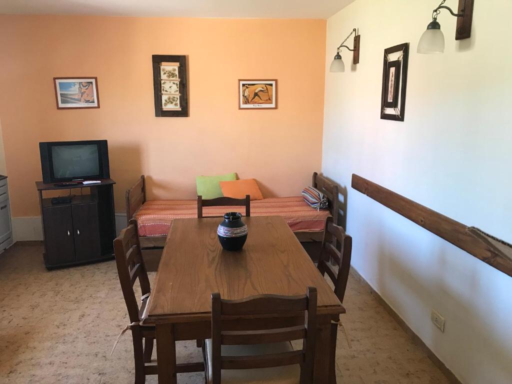 a dining room with a table and a television at Complejo El Pinar in Las Grutas