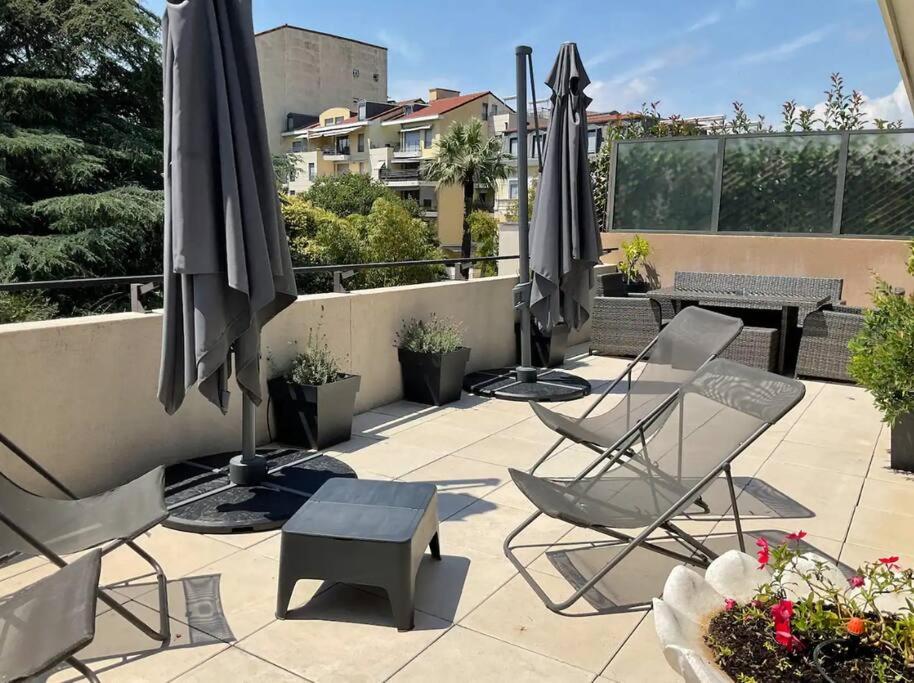 une terrasse avec des chaises, des parasols et une table dans l'établissement Toit terrasse dans résidence avec piscine, à Cannes
