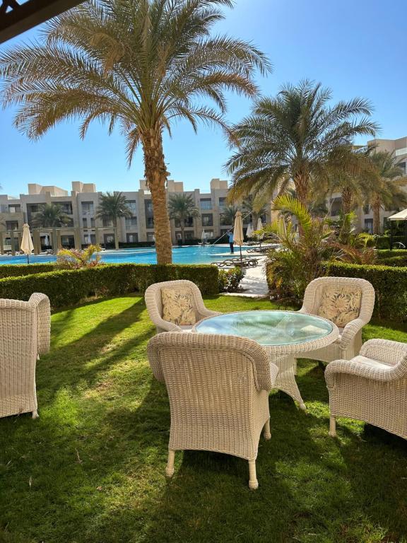 a table and chairs with palm trees in a yard at Mangroovy apartament El gouna in Hurghada