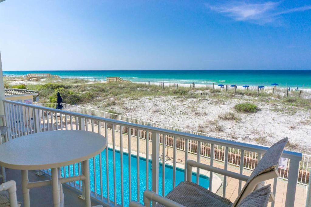 a balcony with a table and chairs and the beach at Beach Front Destin Condo Daily Beach Service - Blue Dolphin in Fort Walton Beach