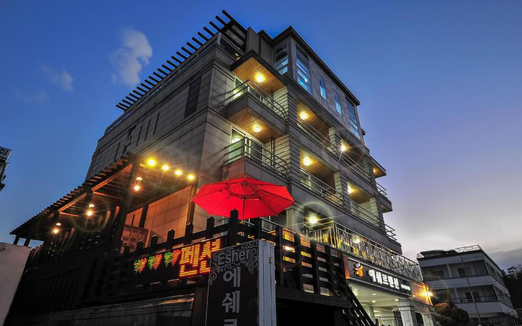 un edificio con un paraguas rojo delante de él en Sokcho Esher House Pension en Sokcho