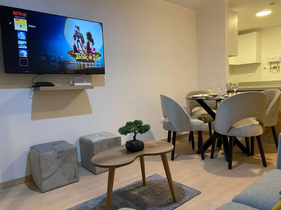 a living room with a table and a tv on the wall at Apartamento en Barranco in Lima