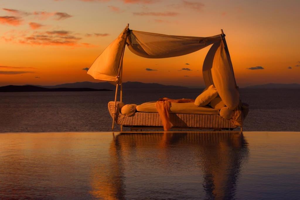 a bed in the middle of the water with the sunset at Mykonos Sea View Luxury villa by Calypso sunset Villas in Mýkonos City