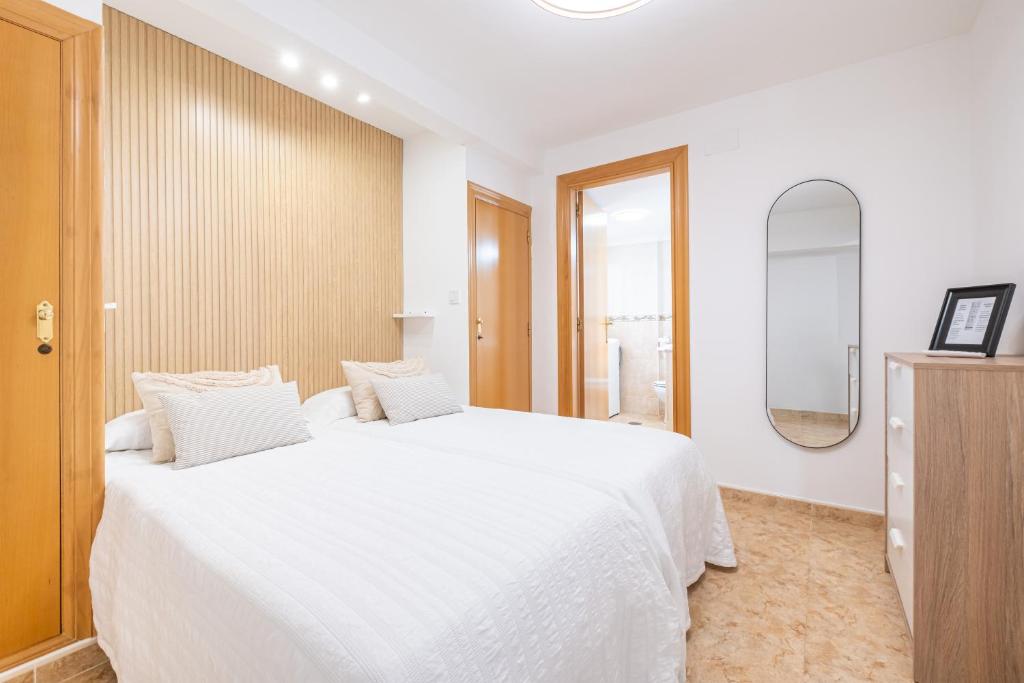 um quarto com uma grande cama branca e um espelho em Apartamento Currus Miramar Playa em Benidorm