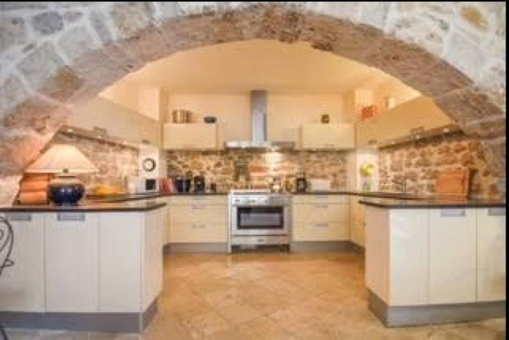 une grande cuisine avec un mur en pierre et une arche dans l'établissement Vérité Maison de Lorgues village center- Charming 2 bed 2 bath oasis, à Lorgues