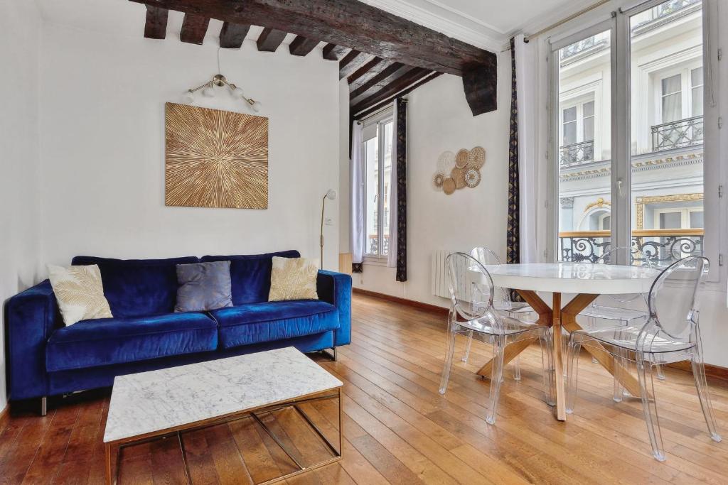 Charming T2 in 2nd arrond of Paris - Welkeys في باريس: غرفة معيشة مع أريكة زرقاء وطاولة