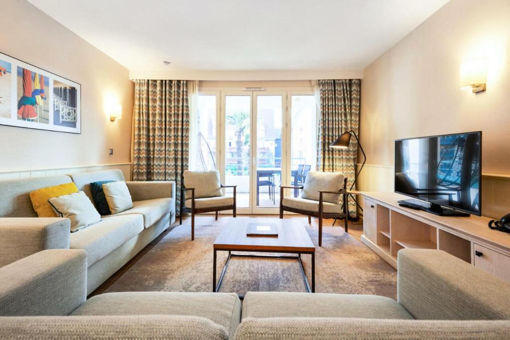 un salon avec un canapé et une télévision dans l'établissement Résidence Presqu'Ile de la Touques - Appartement 3 pièces 6 personnes - Exclusive MAE-5334, à Deauville