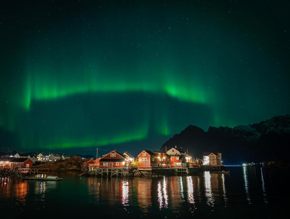 una imagen de la aurora boreal sobre una ciudad en Henningsvær Rorbuer, en Henningsvaer
