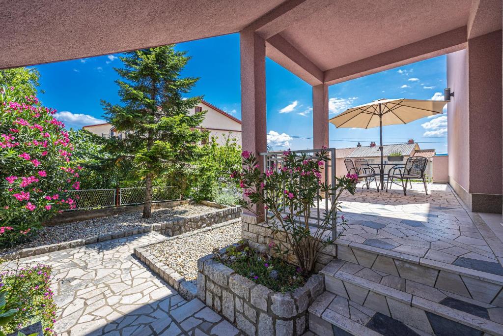 un patio con una mesa y una sombrilla en Apartments ALEXIS, en Crikvenica