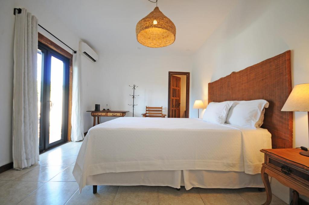 a bedroom with a large white bed and a window at Villa Santa Fé in Búzios