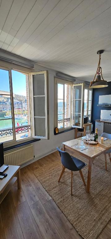 a living room with a table and some windows at L'atelier- Duplex Vue magnifique sur le port- in Saint-Valery-en-Caux