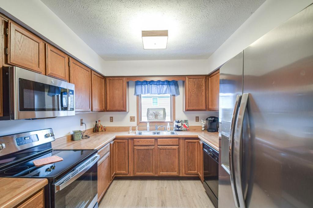 uma cozinha com armários de madeira e um frigorífico de aço inoxidável em Welcoming Condo in Davenport Central Location! em Davenport