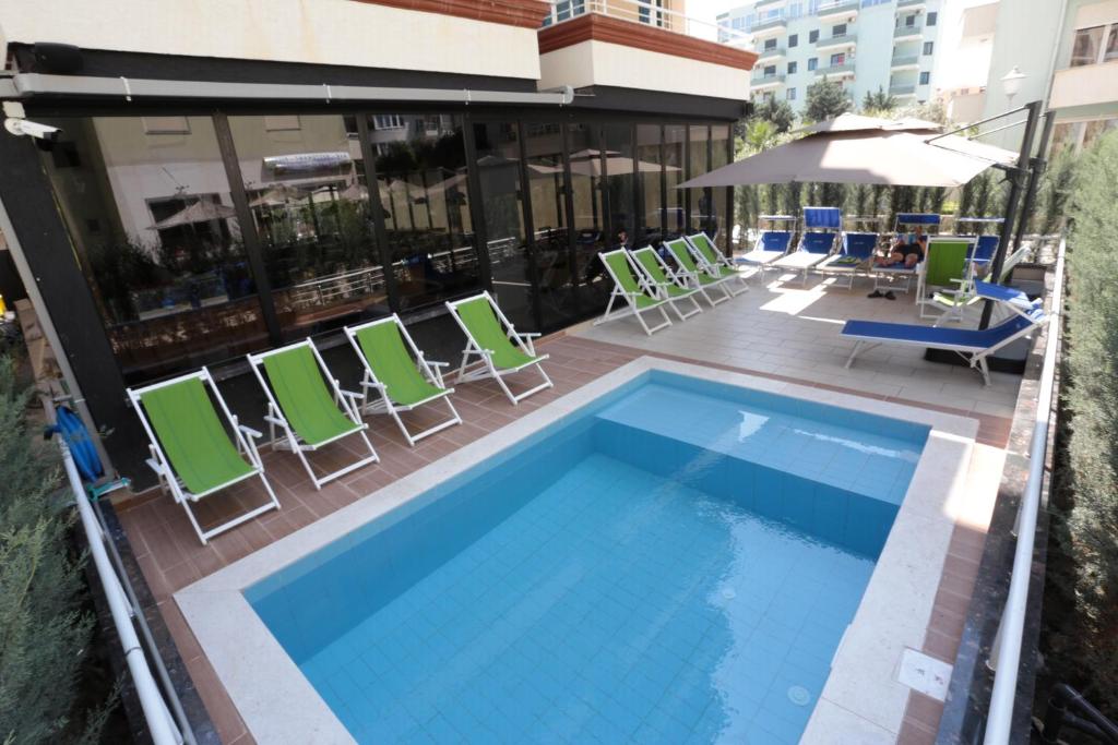 a swimming pool on a balcony with chairs and an umbrella at Alvin Comfort Hotel in Durrës