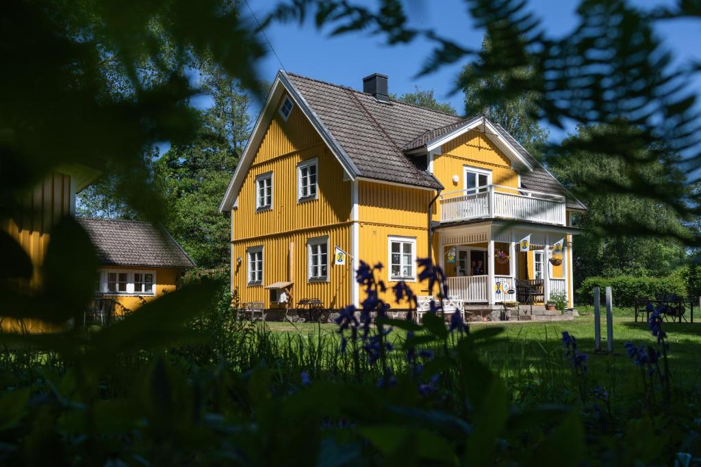 una casa amarilla con techo negro en Söderåsens Skafferi - Logi, en Ljungbyhed