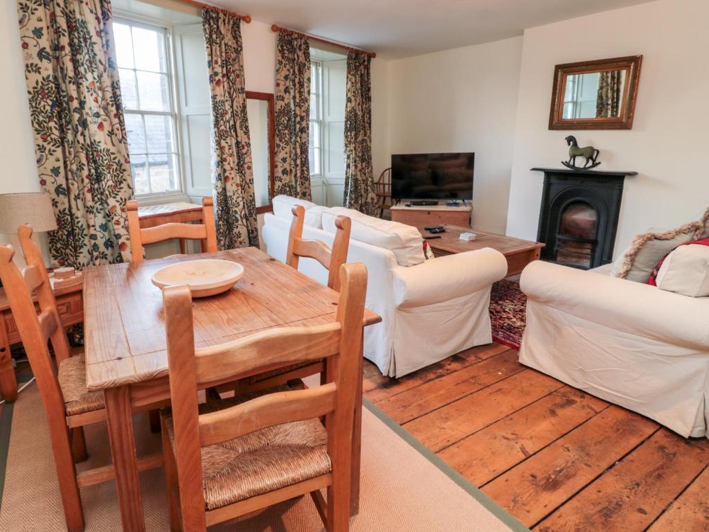 a living room with a table and a fireplace at Upper Oakwood in Alnwick