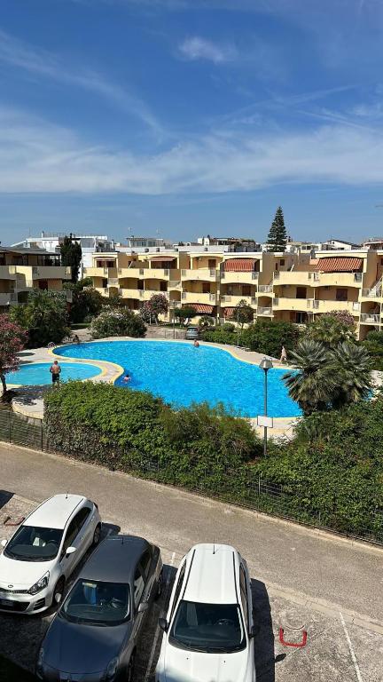 two cars parked in a parking lot in front of a pool at NURAS - DomoDé in Alghero