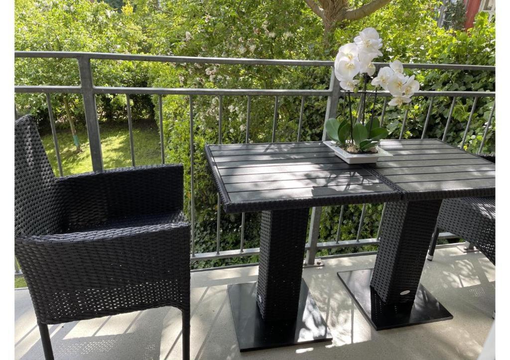 a black table and chairs with flowers on a balcony at Schicke Wohnung im grünen Hinterhof in Schwerin
