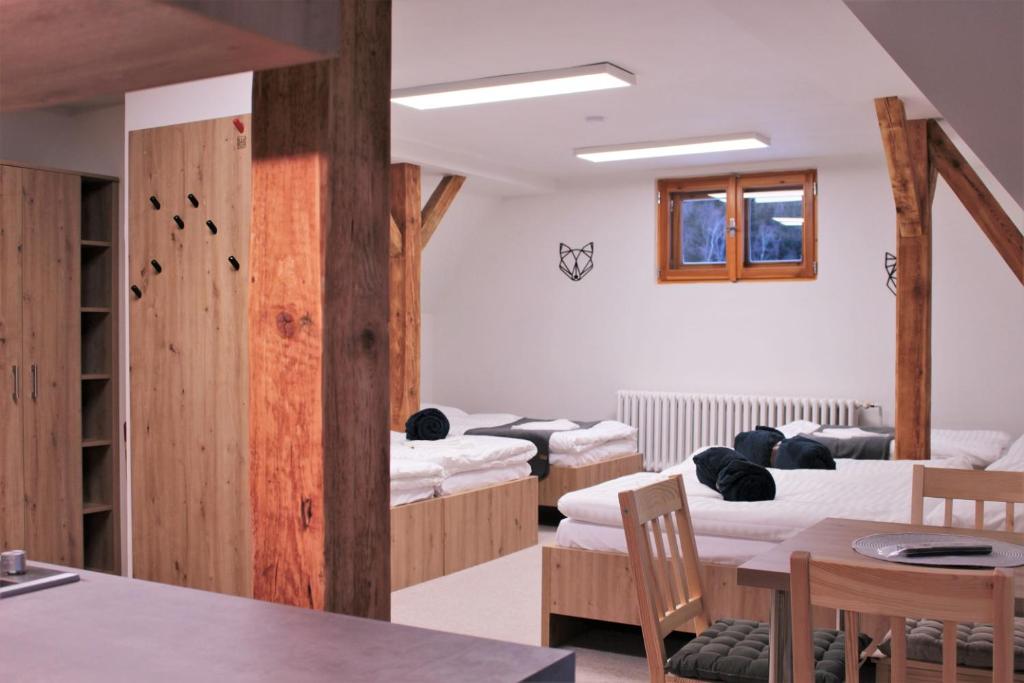 a room with four beds and a table and chairs at Chata Granit, Zadov - Churáňov in Zadov