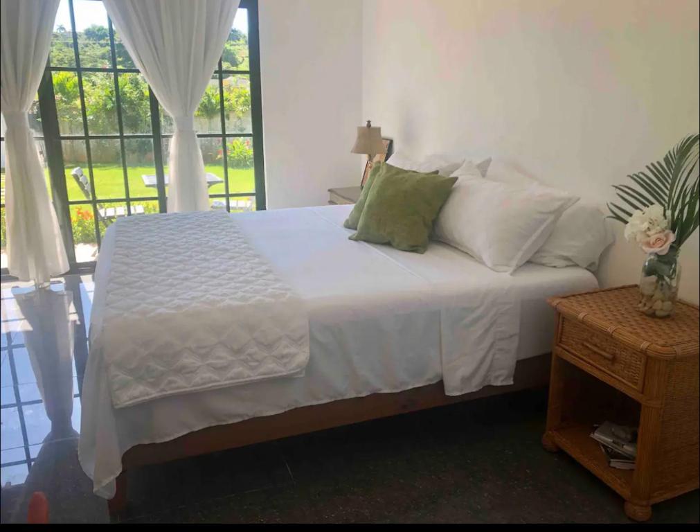 um quarto com uma cama com lençóis brancos e uma janela em Stylish room by the beach em Las Galeras