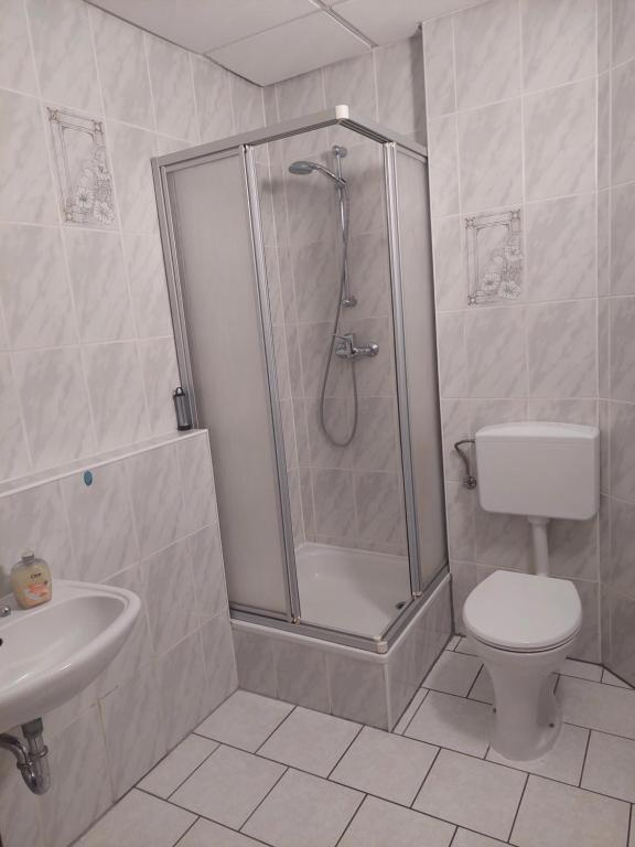 a bathroom with a shower and a toilet and a sink at Hotel Restaurant Rhodos in Elsterwerda