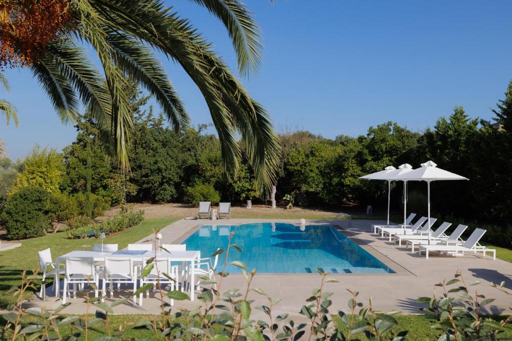a swimming pool with white chairs and an umbrella at Gaia - A Secret Luxury Hideaway in Achílleion