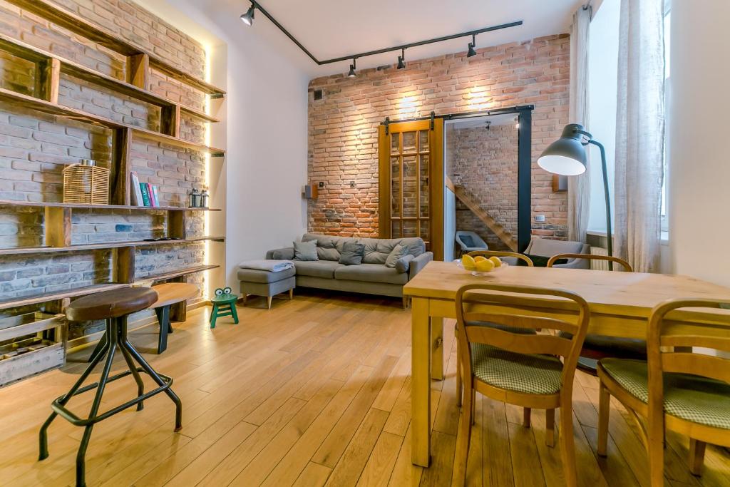 a living room with a wooden table and a brick wall at Warsaw Concierge Metro Loft in Warsaw