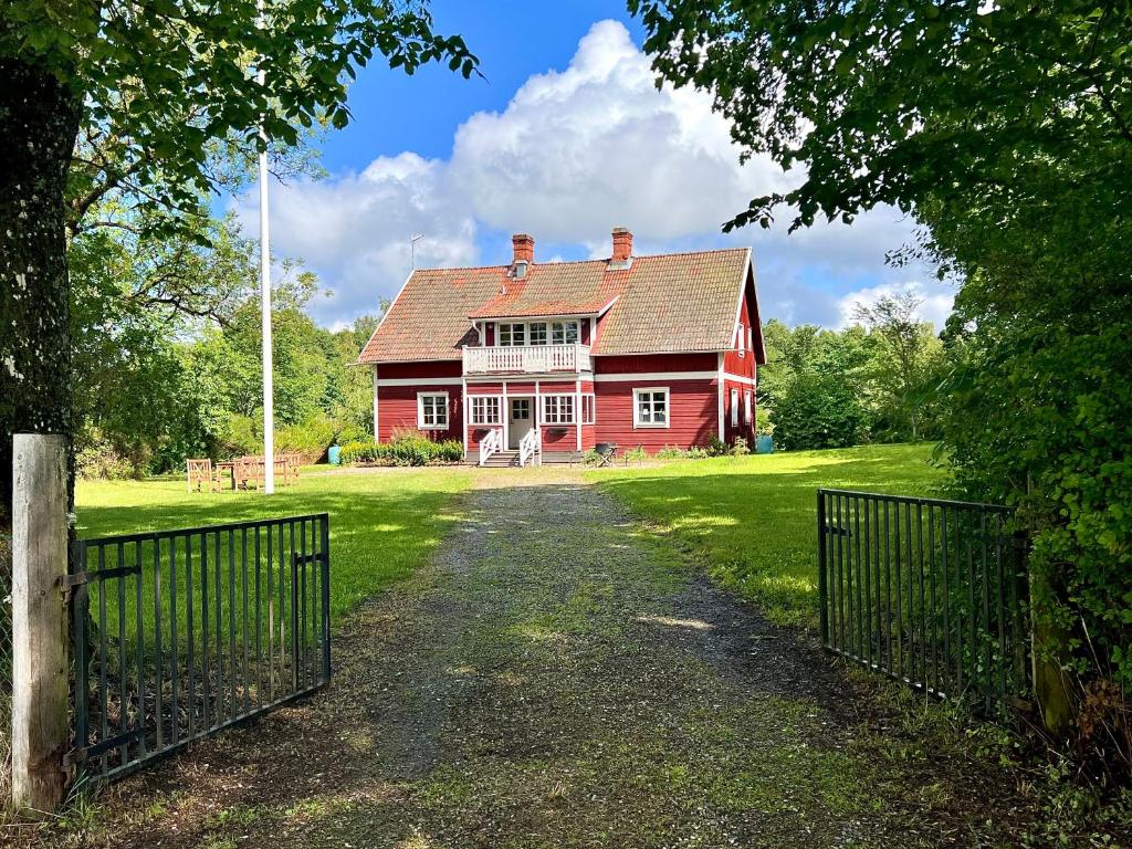 a red house with a fence in front of it at Sjönära lantgård i Bergslagen in Skinnskatteberg
