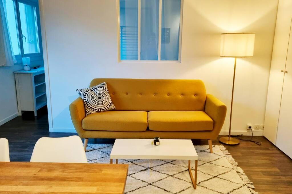 a living room with a yellow couch and a table at Cocon familial proche de Paris in Issy-les-Moulineaux