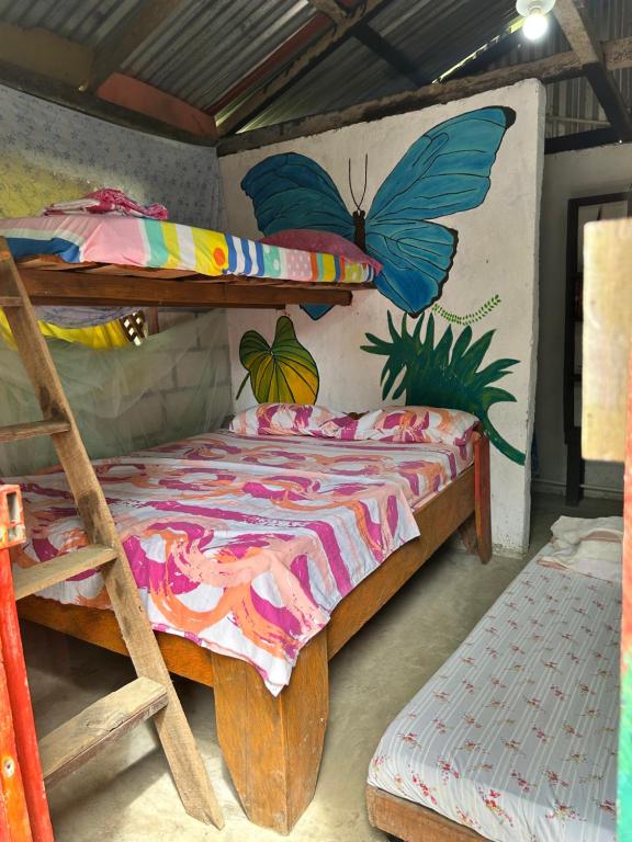 a bedroom with a bunk bed with butterflies on the wall at Posada El Silbo Apacible Cabaña y Camping in Ladrilleros