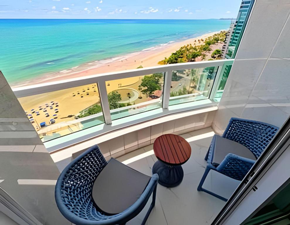 a balcony with two chairs and a table and the beach at Flat Radisson Recife in Recife