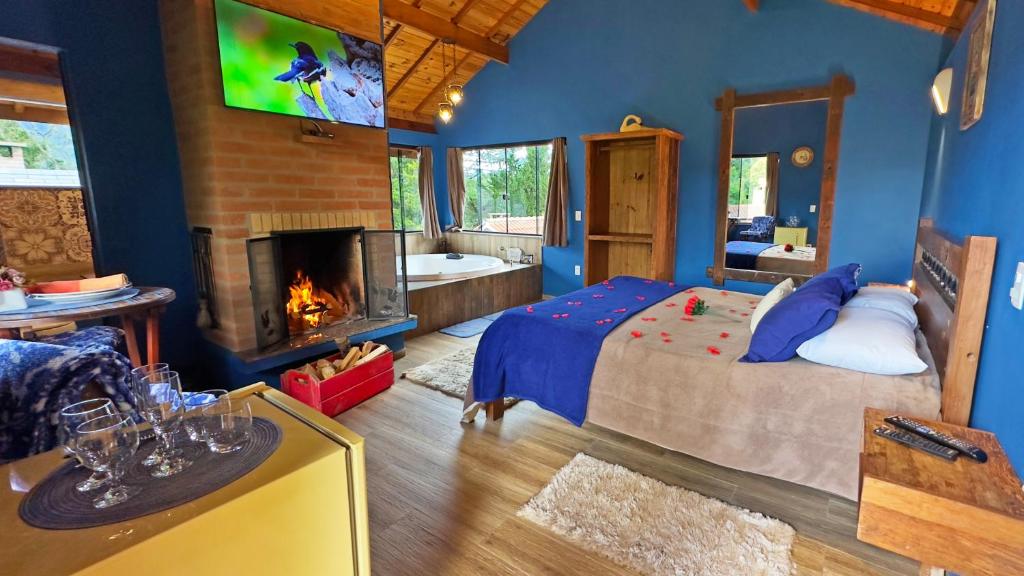 um quarto com uma cama, uma lareira e uma televisão em Chalés Mirante das Pedras em Monte Verde