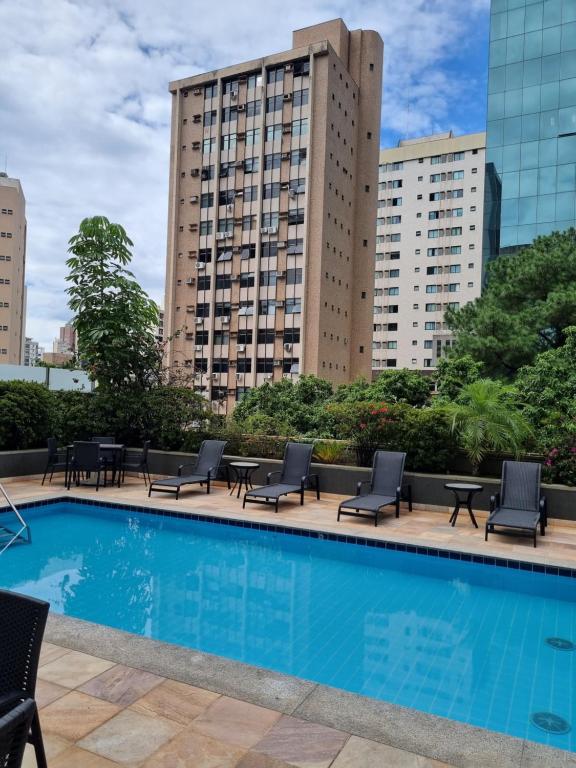 a hotel pool with chairs and tables and buildings at Max Savassi Glamour in Belo Horizonte