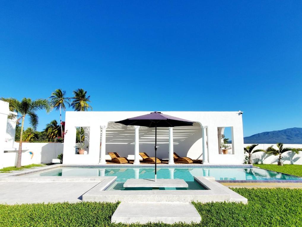 uma piscina com um guarda-sol ao lado de uma casa em CASA ROMA Hotel Boutique em El Tamarindo